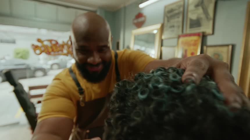 A barber shaves a customers head with an electric razor in a barbershop