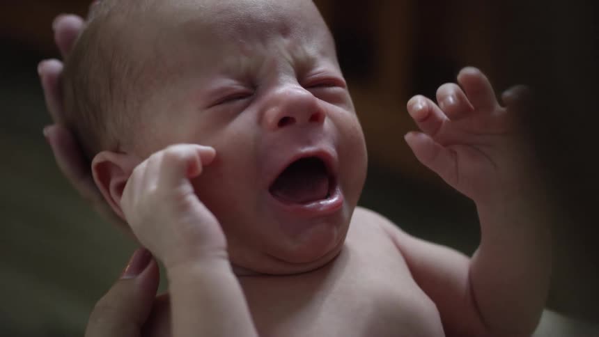 Close up of a baby crying in their mothers arms