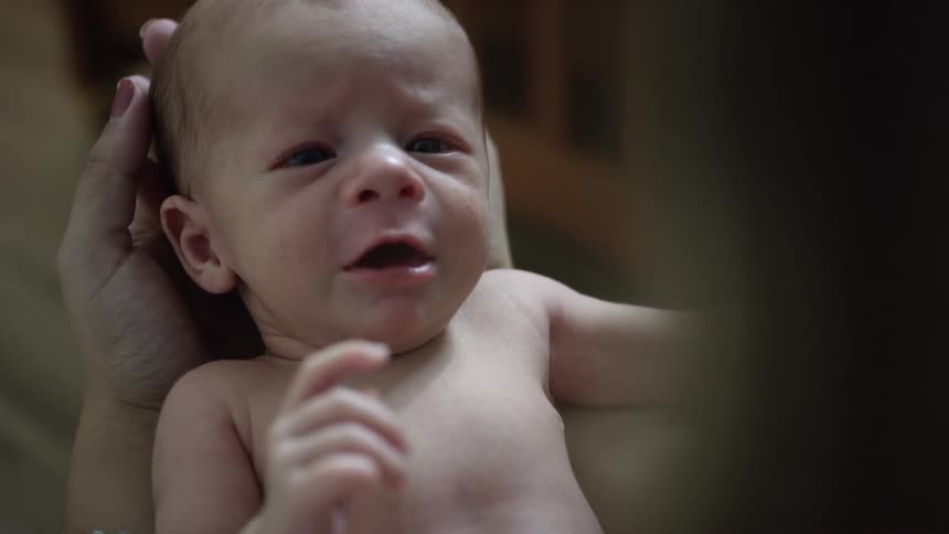 The baby is reaching his hand towards his mom