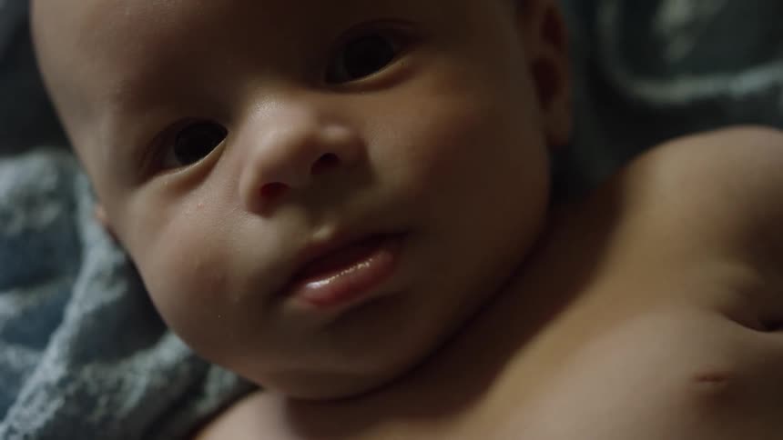 A small baby from the chest up laying on a blanket