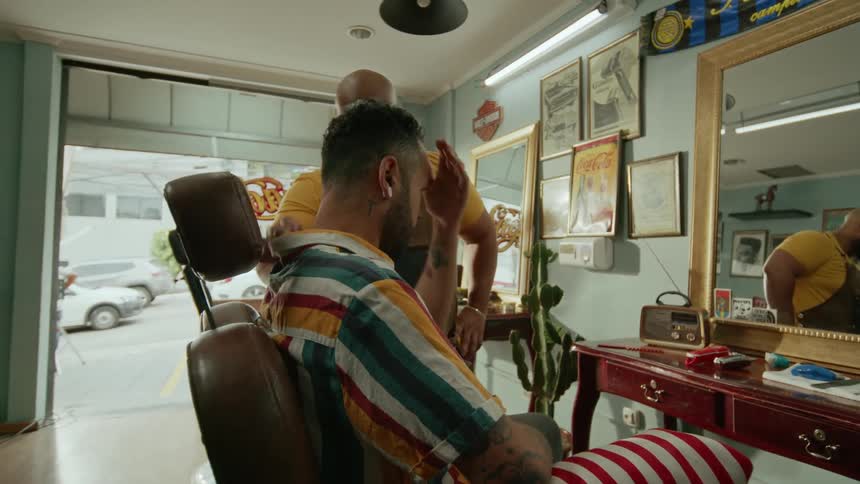 A barber warmly greets his client in a cozy retro style barbershop
