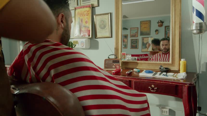 A barber is showing mirror to his client so that he can see his back head haircut and also styling his hair