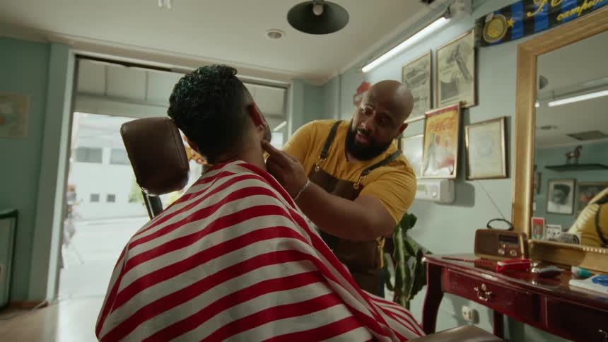 A barber styles a client hair inside a vintagestyle barbershop