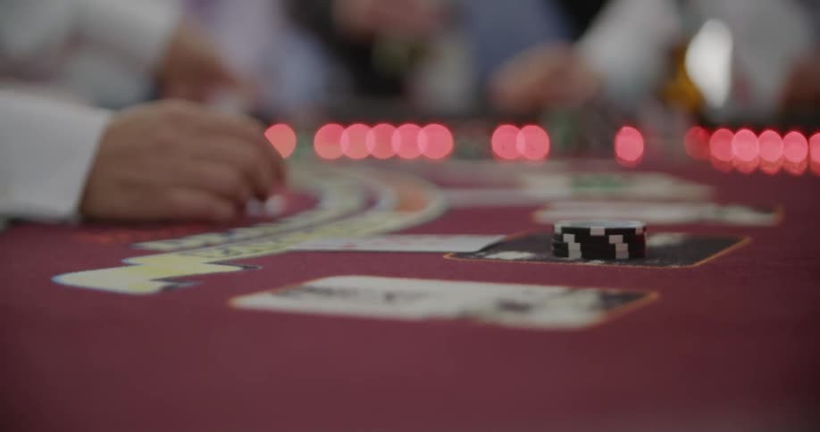 A close up view of a casino table with cards, lights and people playing