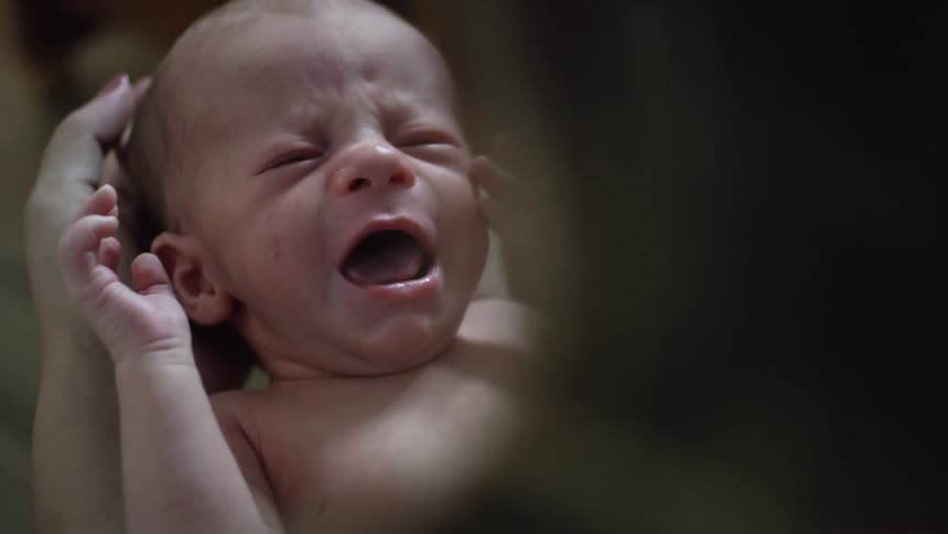 A mother is holding a crying baby