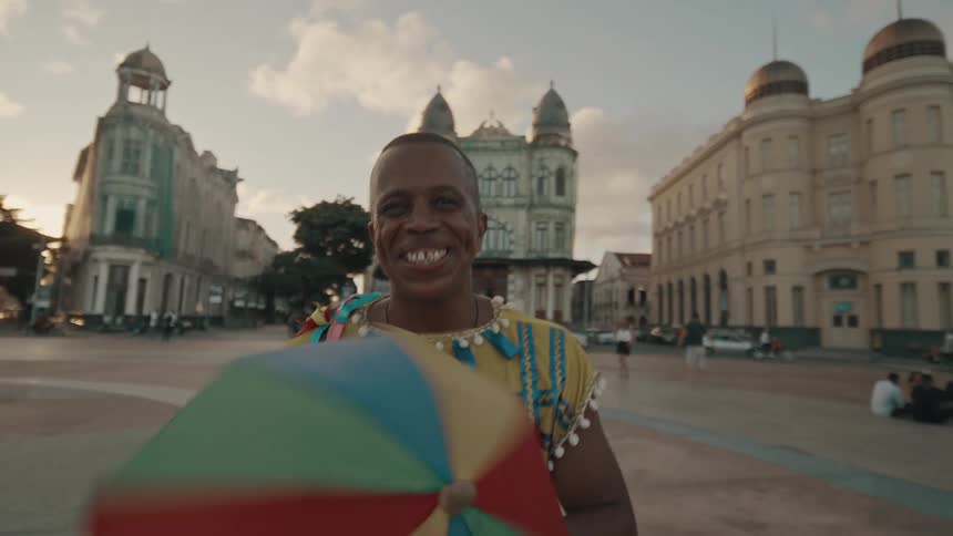 Smiling man in traditional clothing dancing in a square in the city