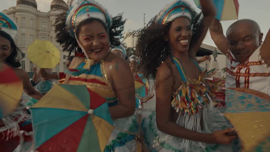 People in colorful costumes dance and celebrate at a lively outdoor festival