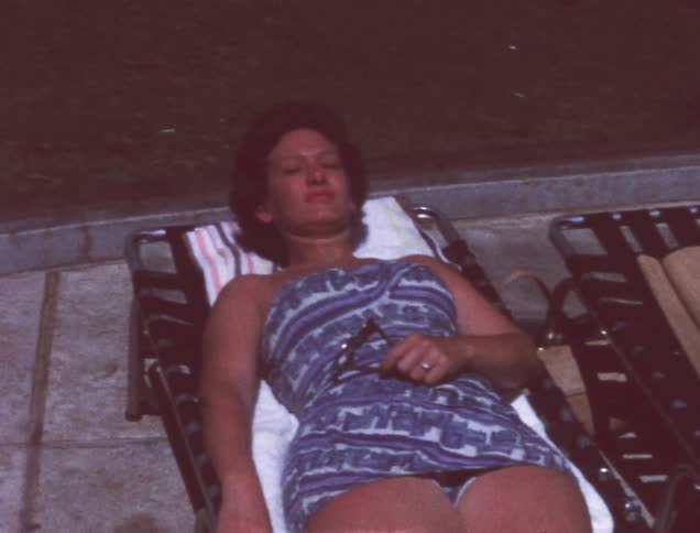 A woman in a bathing suit looks up and waves her hand