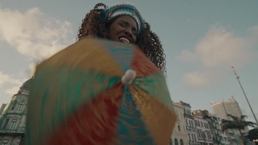 Woman with curly hair and happy expression dancing outdoors in the city