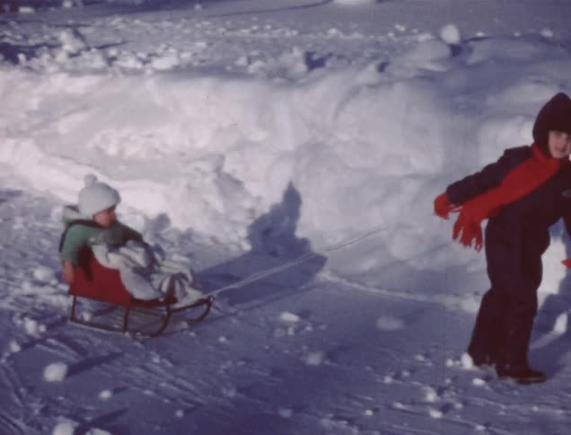 A boy drags a baby in a small sled