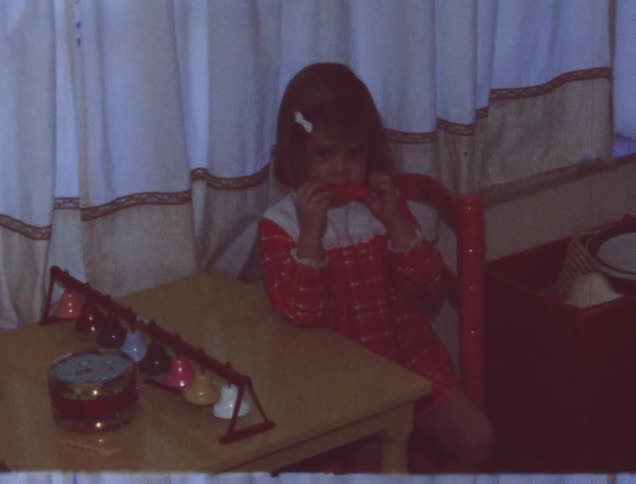 A baby is playing with toys as a girl watches