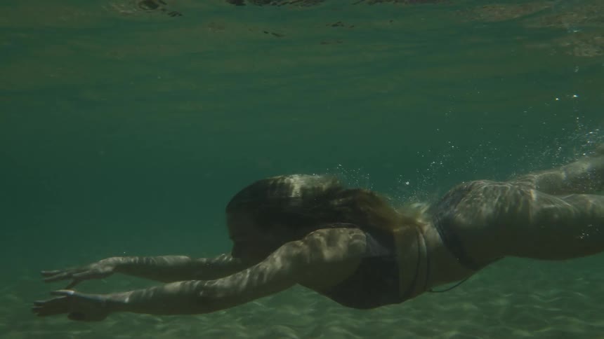 The woman dives underwater and swims