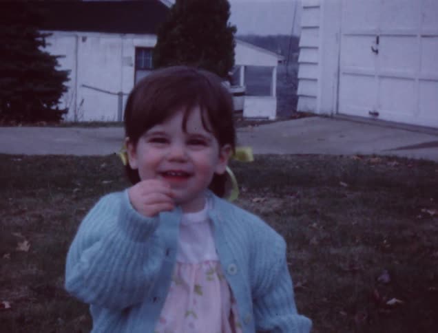 A young girl smiles and waves