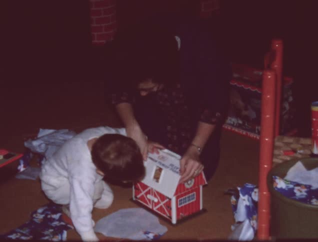 A child and mother examine a toy barn together