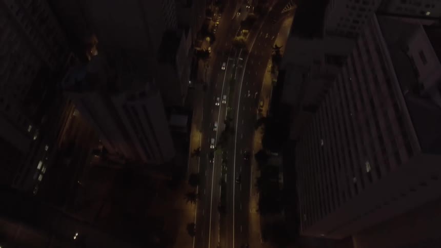 A highway leads to a panoramic view of a city skyline at dusk shows numerous tall buildings with illuminated windows and streets