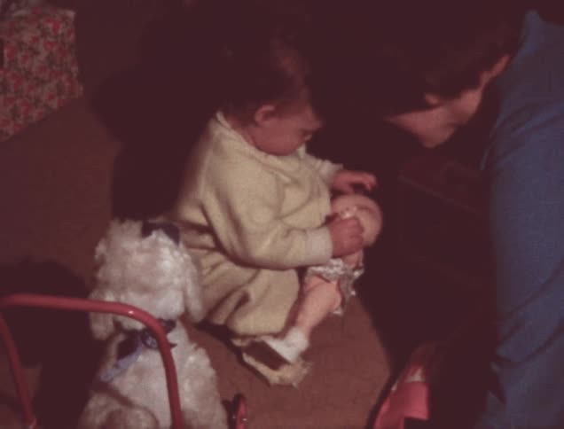 A baby receives a doll and plays with it