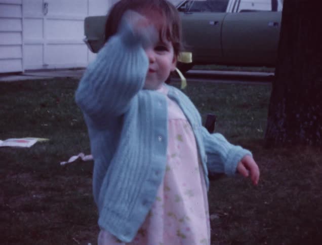 Toddler girl standing and smiling in yard at home