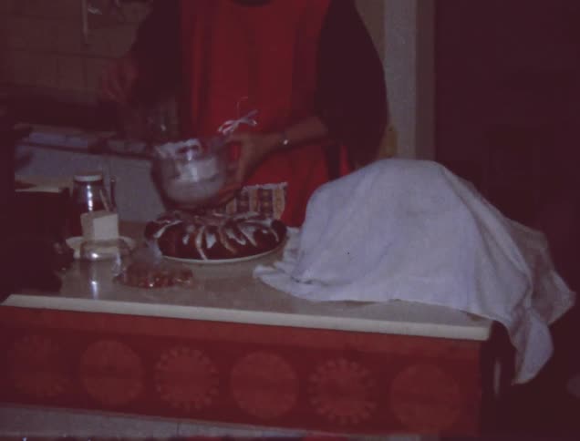 A woman ices a cake in the kitchen