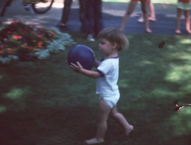 A few children running around and playing with a ball in the yard