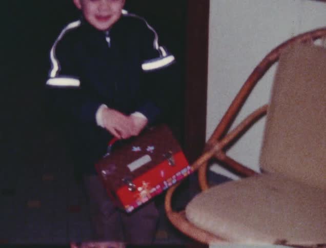 A young boy picks up a pail from a chair