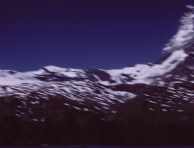 A ski lift is surrounded by snowy mountain peaks