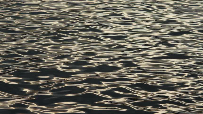 Close up of flowing waves over a calm body of water during daytime