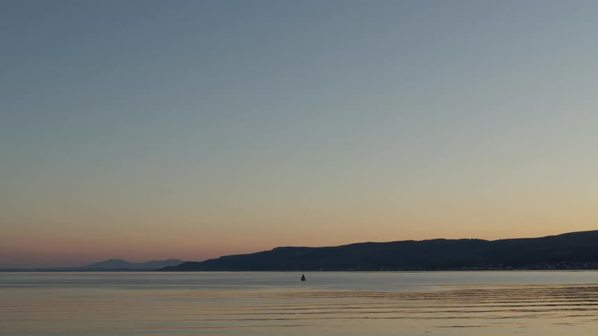 An ocean view at sunset with gentle waves forming ripples