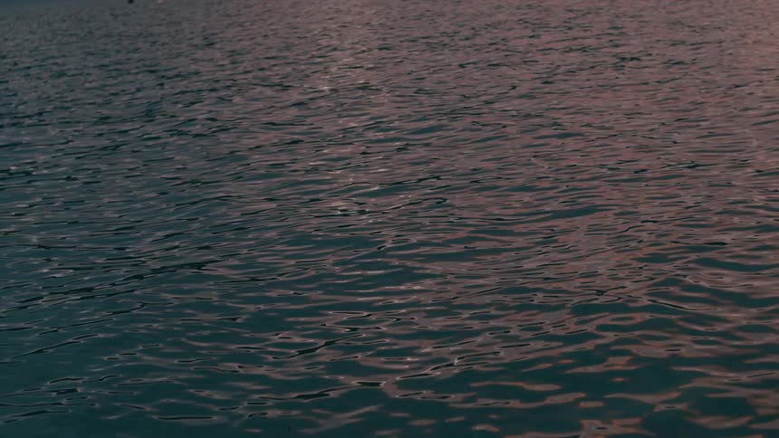 Calm waves on the surface of a large water body at sunset