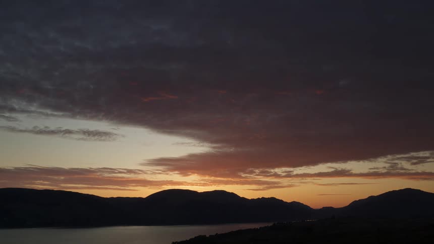 Dramatic sunset over silhouetted mountains and a calm lake