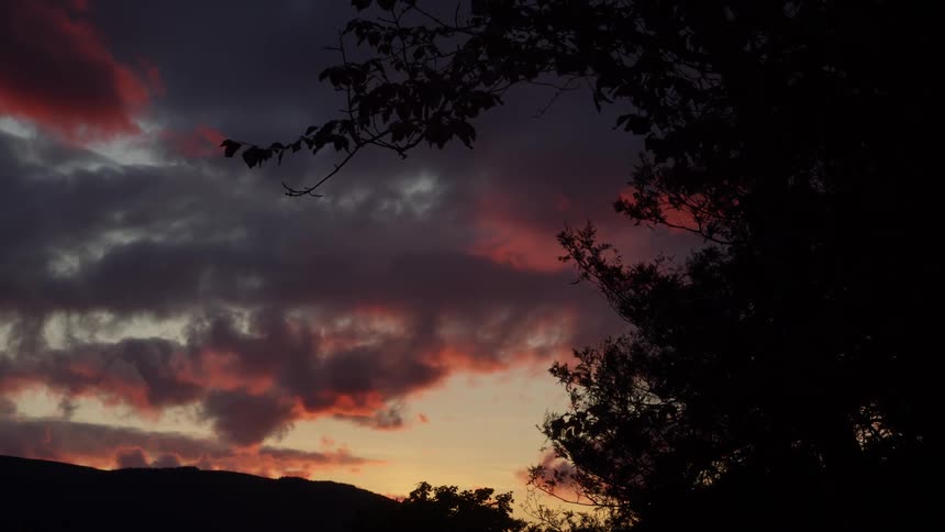 On a cloudy evening the sky remains orange from the setting sun as dark clouds partially cover it