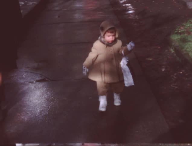 An old film of a person and a child walking down the street carrying a bag