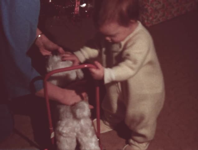 A mother helps a toddler unwrap and get on a new toy