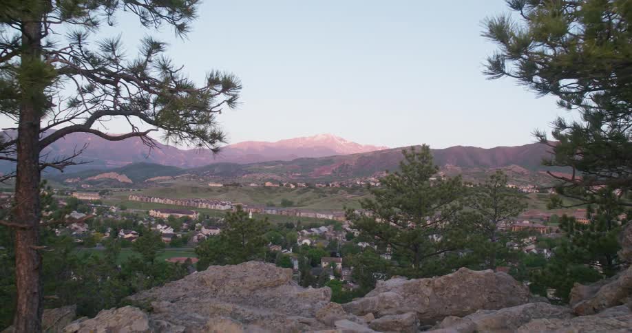 Scenic view of a suburb in a valley with pine trees and sunlit mountains