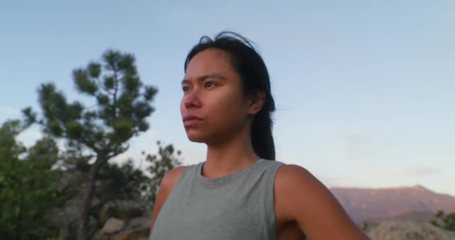 A woman takes deep breaths outdoors in the wilderness