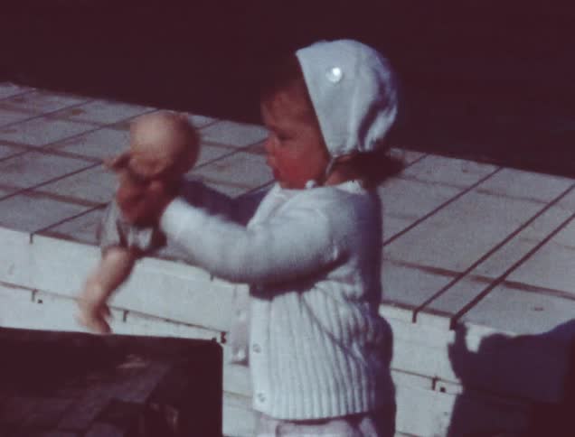 A baby is carrying a small doll