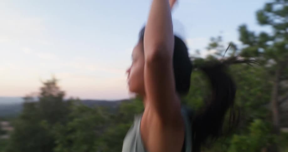 A woman stretches and does jumping jacks during a workout in nature