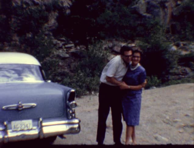 A man and woman holding hands and hugging near a car