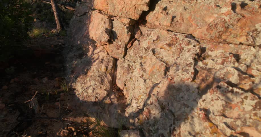 Camera approaches a rock face as a shadow runs past