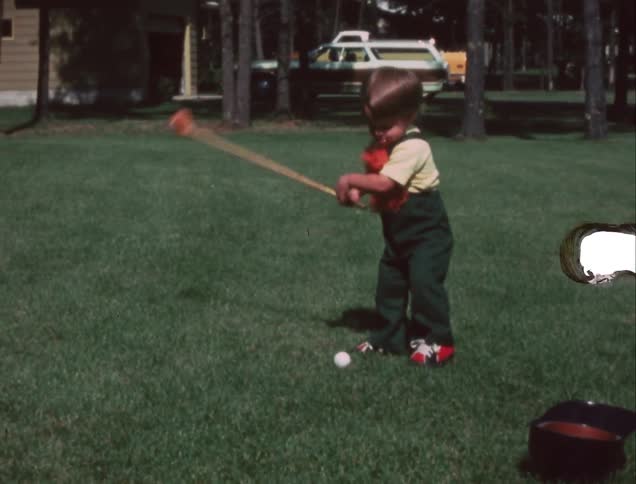 A child playing with a ball and golf club in their yard