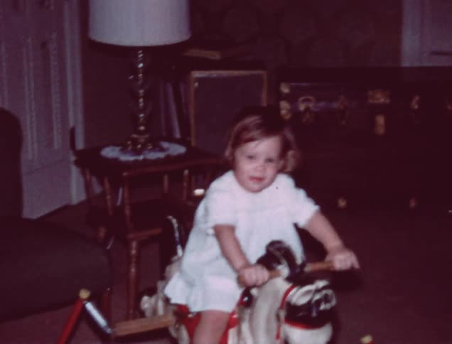 A little girl rides a rocking horse