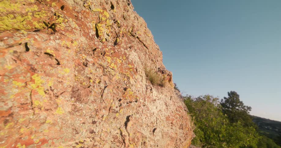 A mountainous rock is surrounded by trees at midday