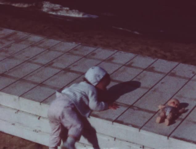 A child crawling and walking around outside on a sidewalk