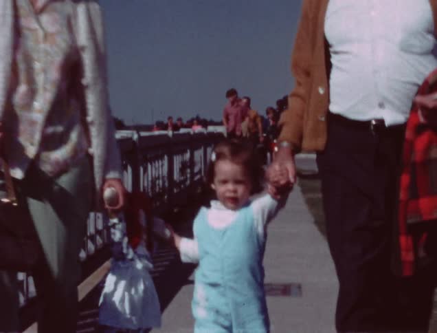 A child holds hands with her grandparents