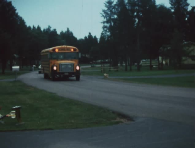 School bus with lights flashing driving down a neighborhood road