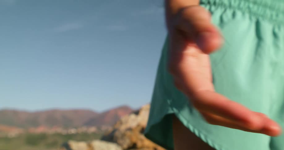 The woman waves her hands at her side on the mountain