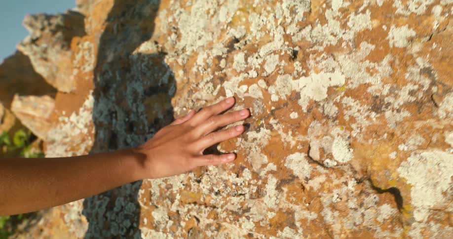 Persons hand being passed over a rock
