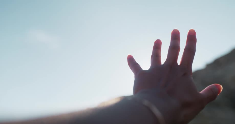 A person reaches up and covers the sun
