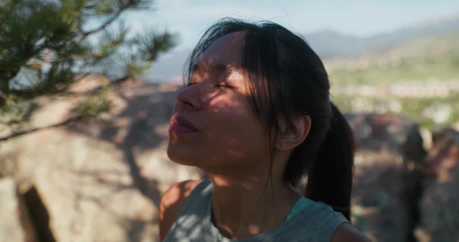A woman sitting under a pine tree taking deep breaths while contemplating nature
