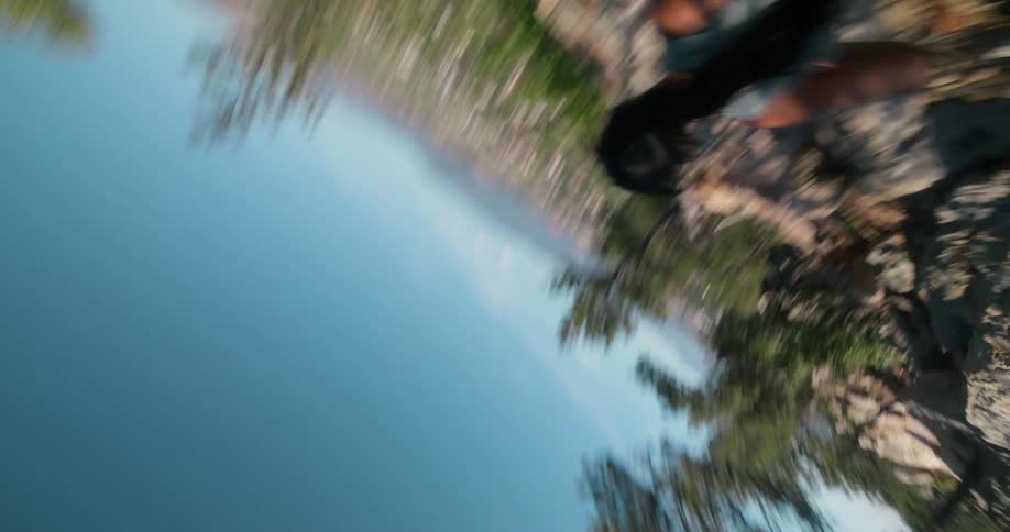 A dynamic lowangle shot of a person running uphill on a dirt trail under a bright sky it then abruptly transitions to a vertigoinducing inverted perspective of someone climbing on a rock face with a sprawling town visible in the distant background