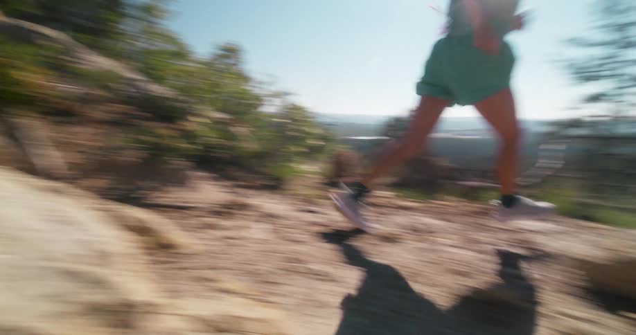 Woman in shorts running on a mountain trail